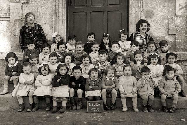 1950 - La classe enfantine, la maîtresse Ginette Jacquet et Élia Setze, la dame de service, posent pour la photo.|Archives Jean-Paul Epinette